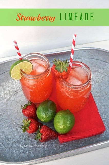 strawberry limeade in two main jars next to strawberries and limes