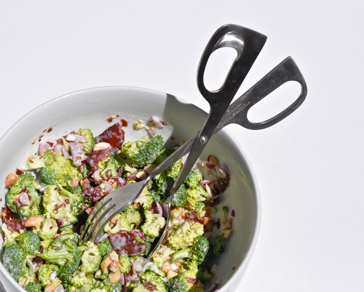 healthy broccoli salad recipe in white bowl with tongs