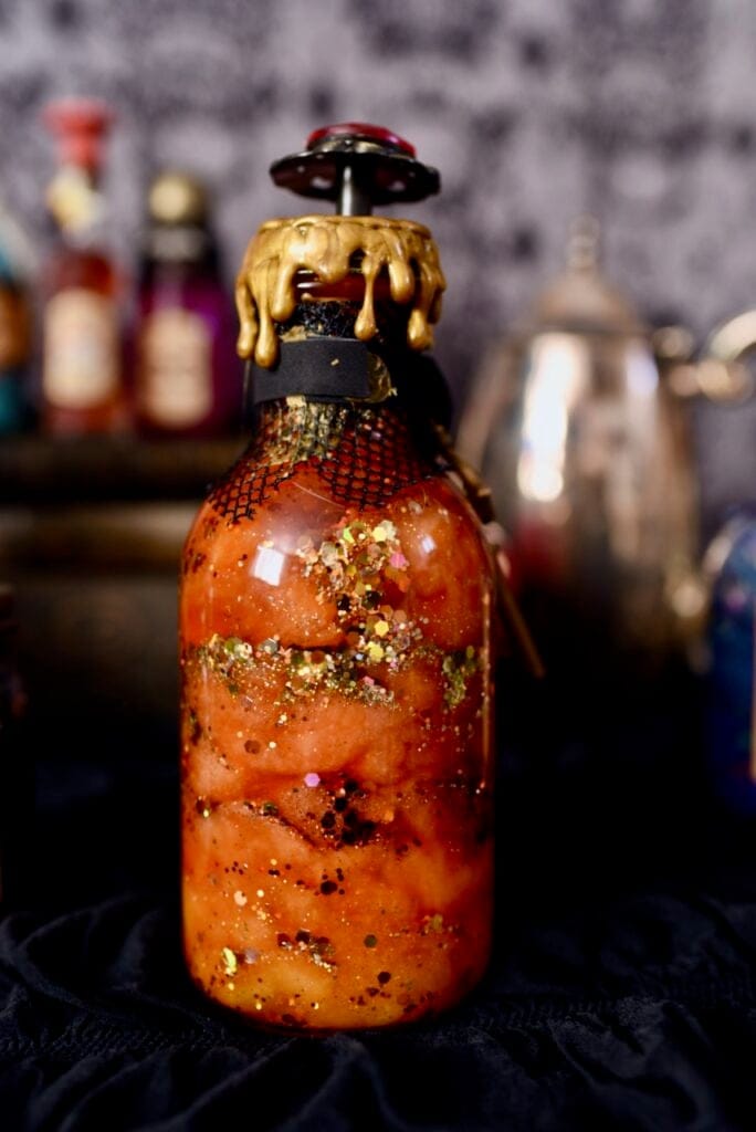 Potion in glass bottle with orange liquid and gold glitter