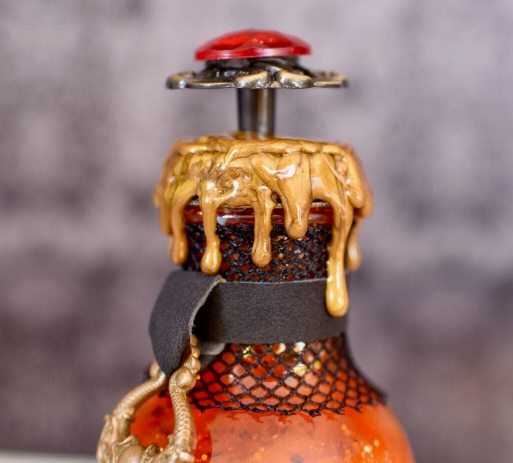 Gold wax dripping down top of glass bottle