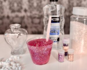 Cup filled with pink glitter gel with spoon inside