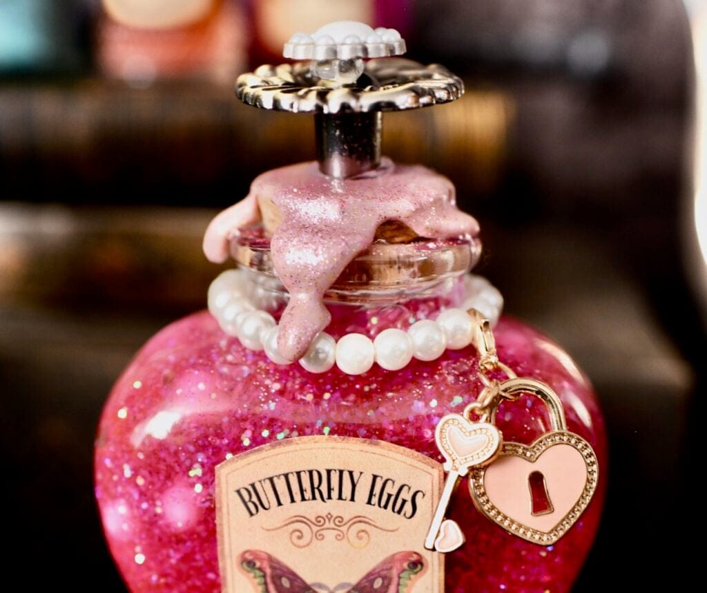 Pink wax and pearls with two charms on top of glass bottle