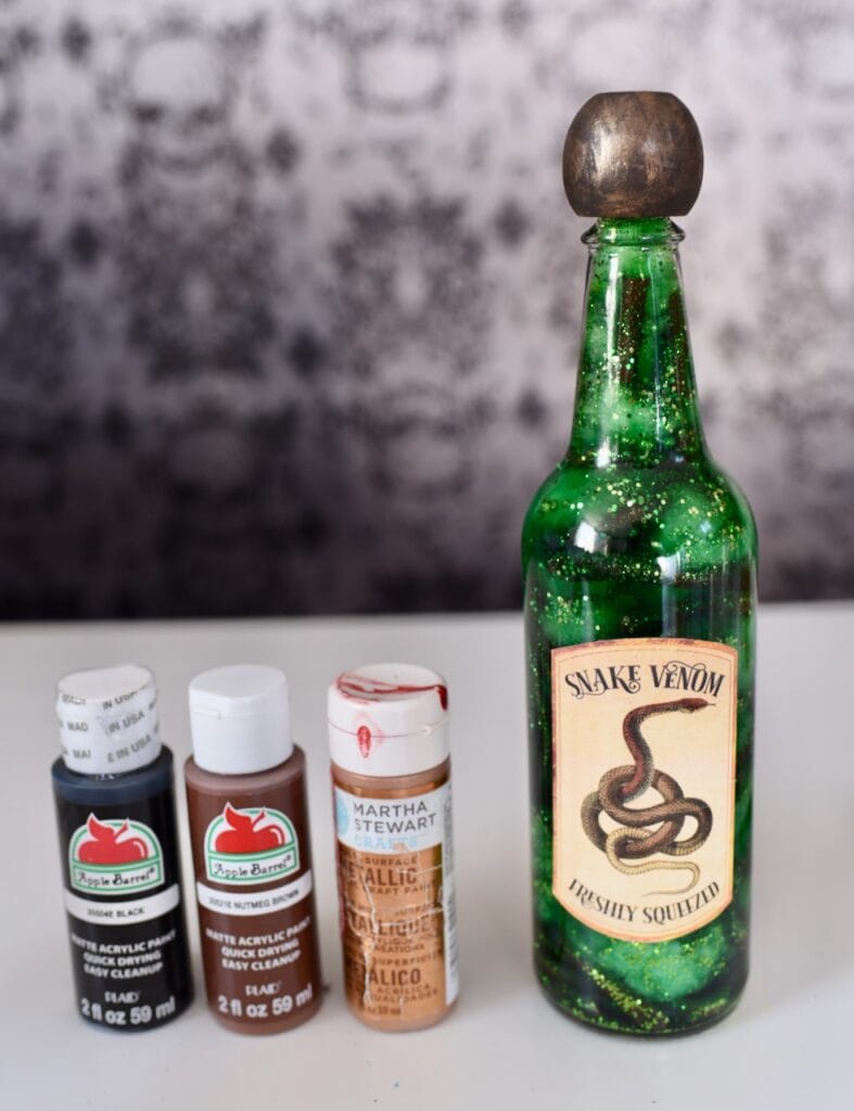 Green liquid in bottle with snake venom label next to craft paint