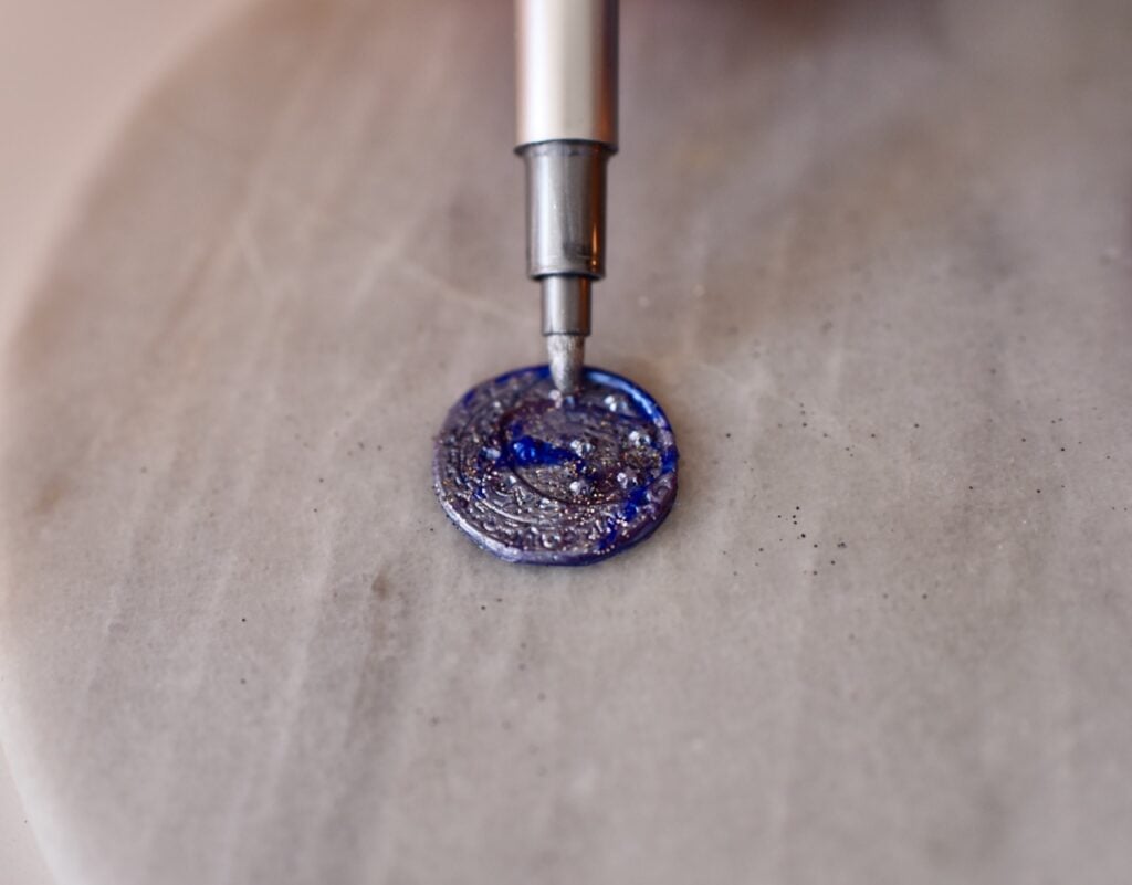 SIlver marker writing on blue and purple wax seal