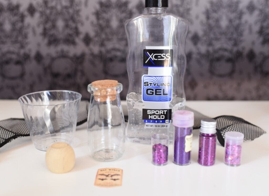 hair gel, purple glitter, and glass bottle on white table