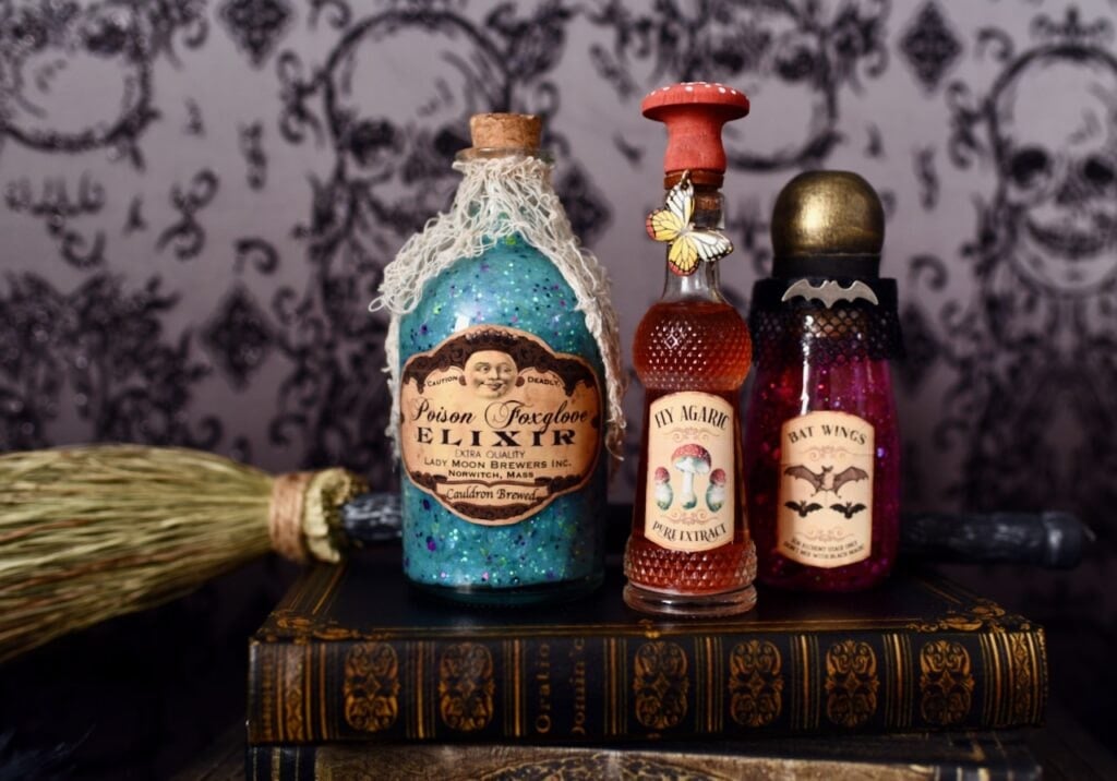 three potion bottles on stack of books with broomstick