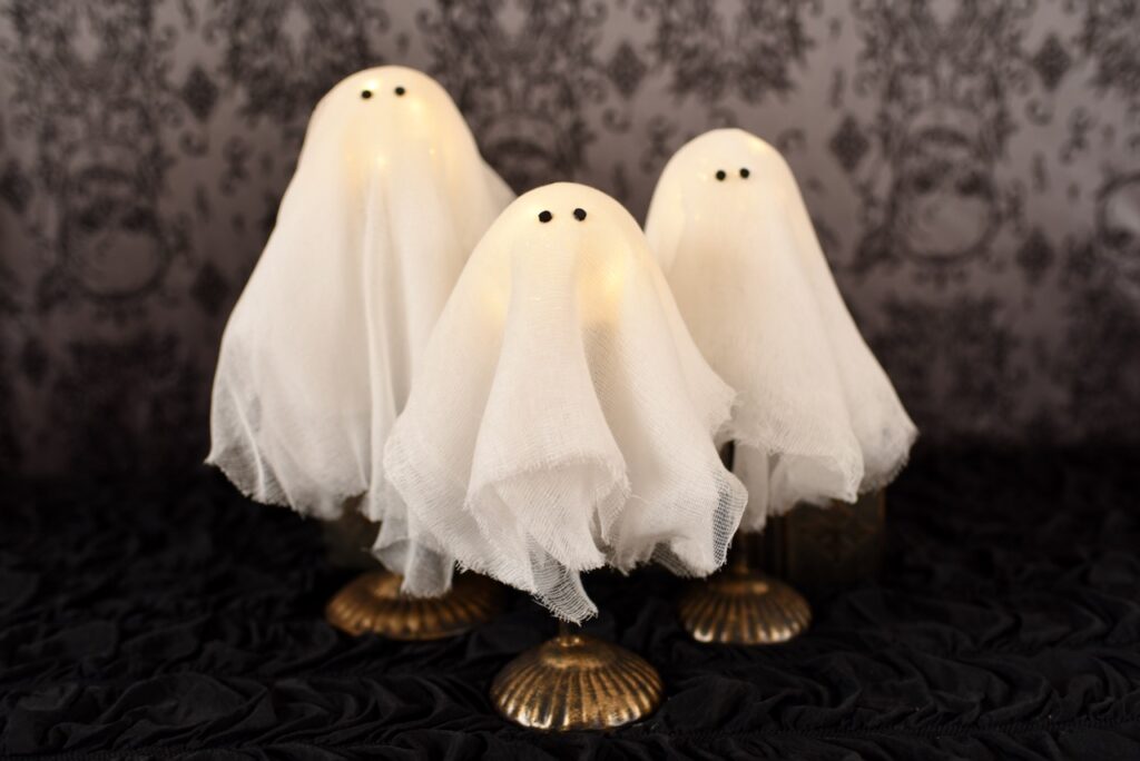 three diy ghosts on stands on black table