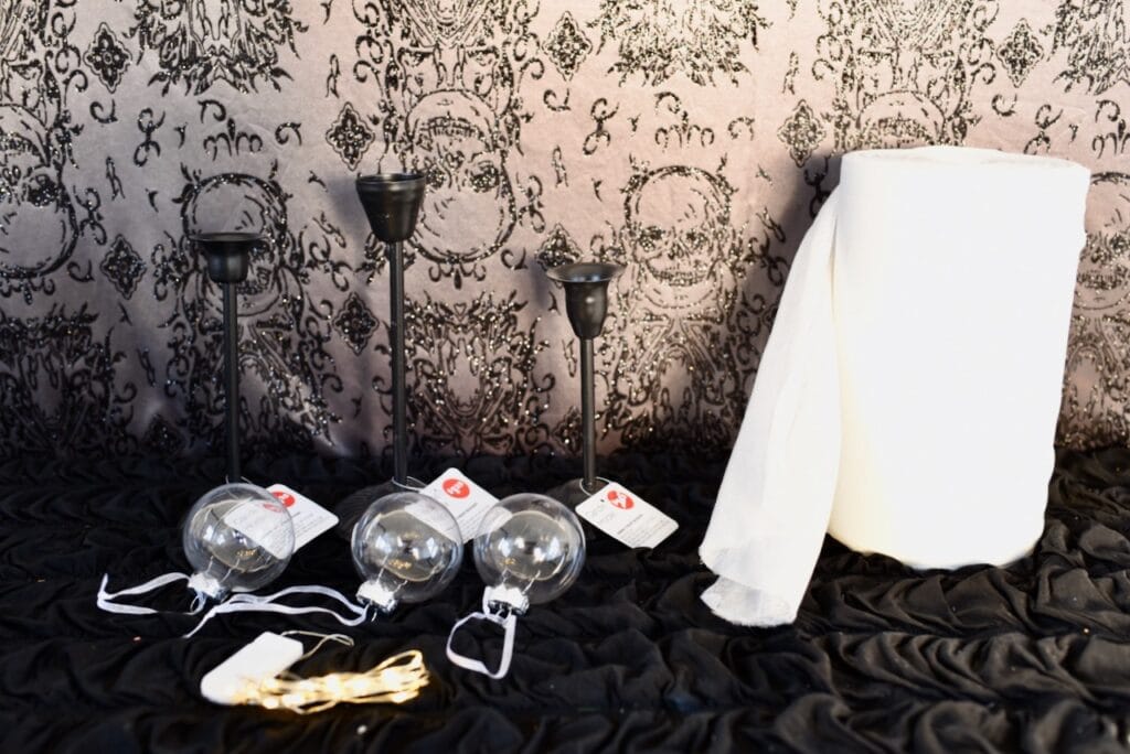 roll of cheesecloth next to black candle holders and clear bulbs