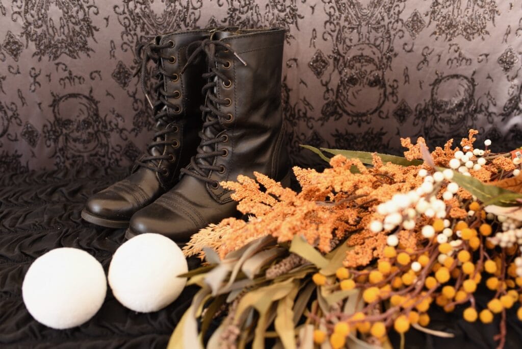 black boots next to orange and yellow fall flowers