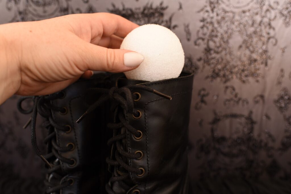 handputtinsg white foam ball inside tall black boot