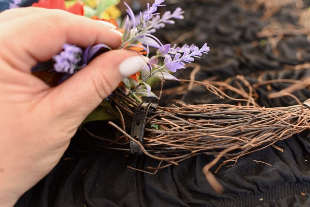 hand holding purple flowers next to moon wreath