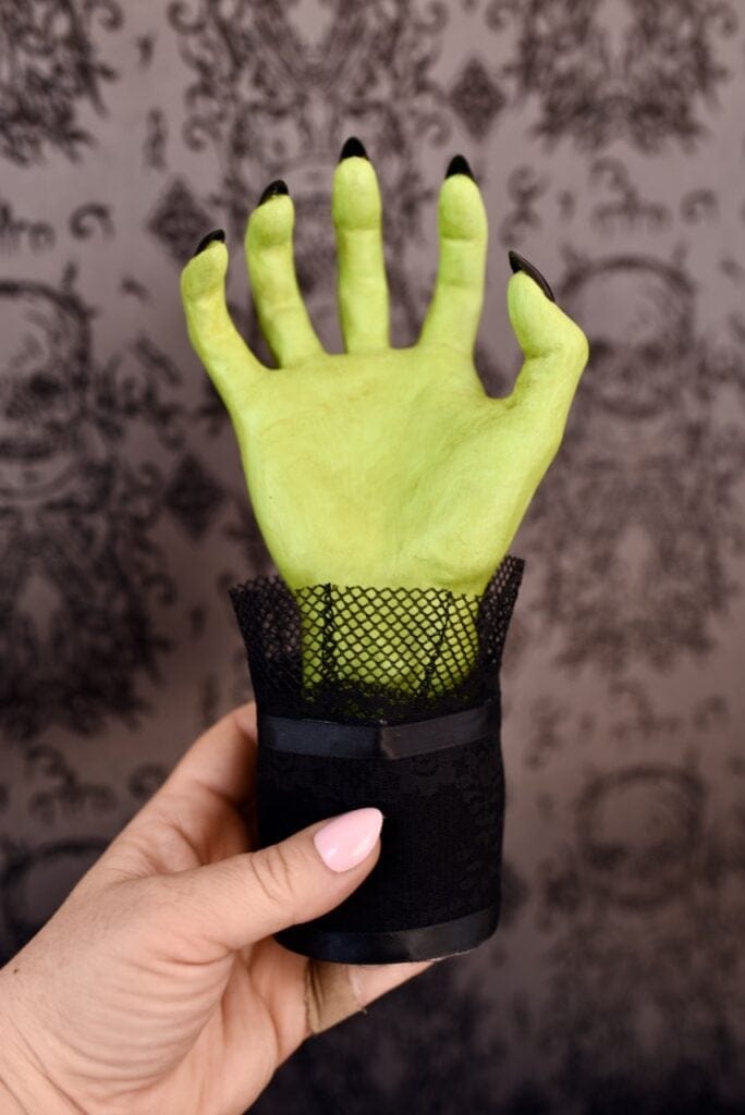 green Halloween hand with black nails and black sleeve