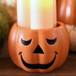 smiling orange jack o' lantern with three lit candles inside