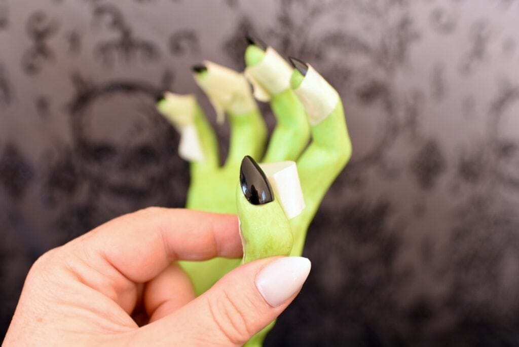 green fake hand with black fingernails