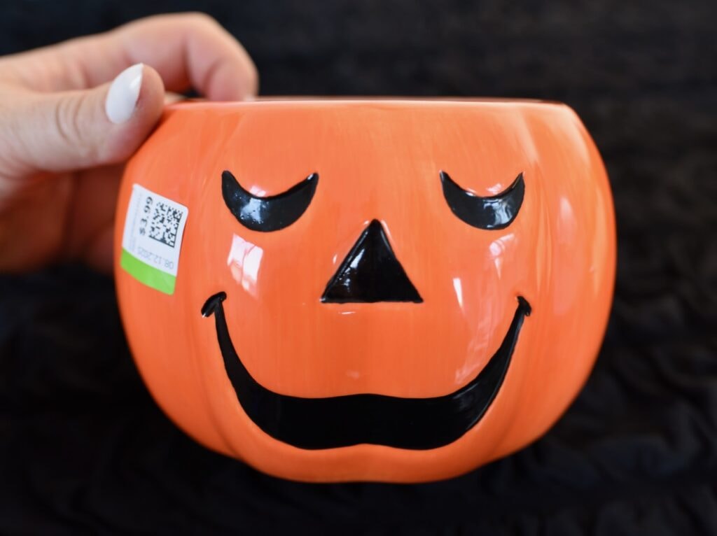 hand holding orange ceramic pumpkin