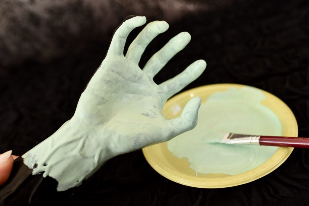 paintbrush and green paint next to green Halloween hand