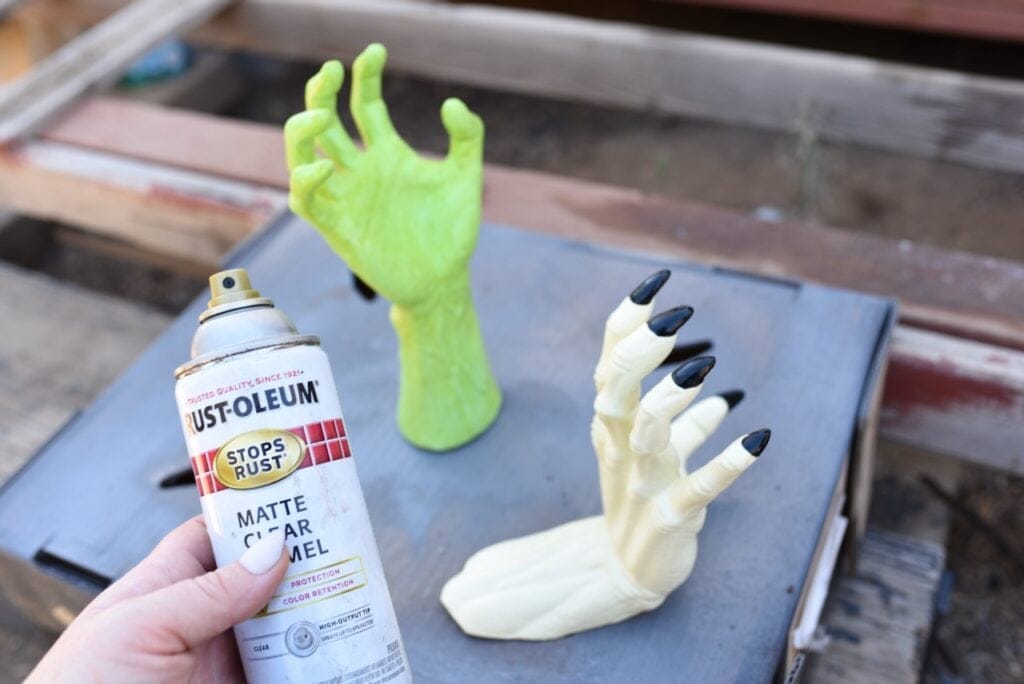 green and white Halloween hands on cardboard box next to spray sealer