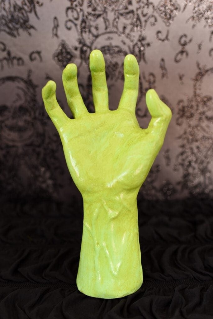 green witch Halloween hand on black table